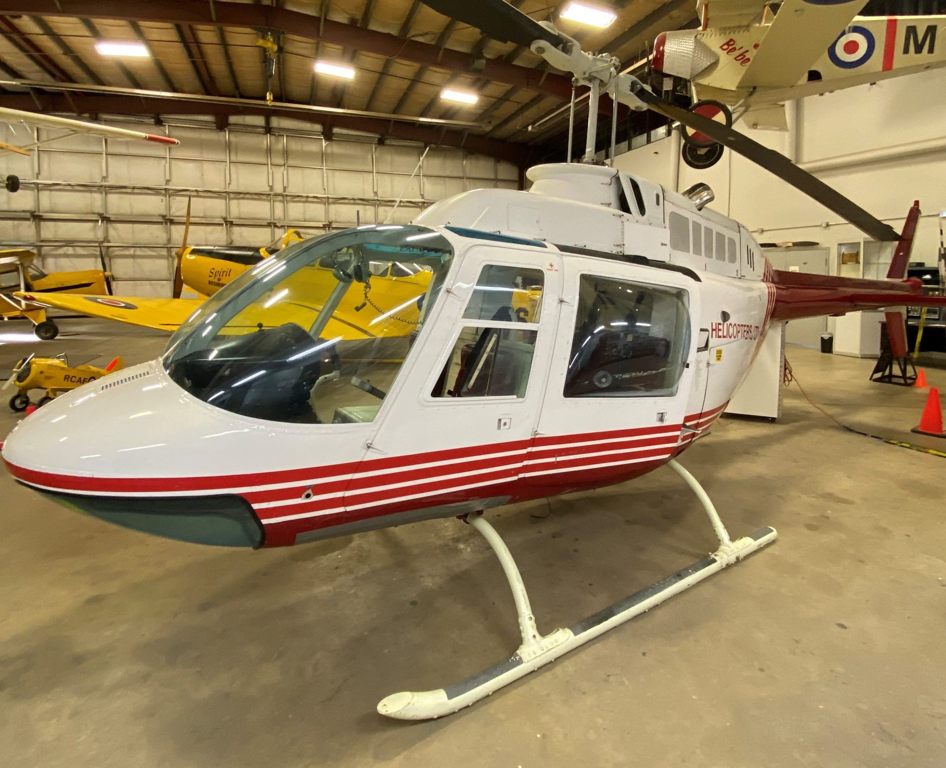 White and red Bell 206B helicopter in the museum hangar